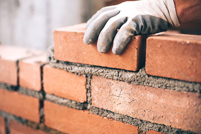 Close Up Of Industrial Bricklayer Installing Bricks On Construct